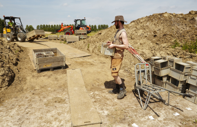 De afgegraven grond wordt in bakken naar de zeefinstallatie gebracht. (Foto: Kris Vandevorst, OE)